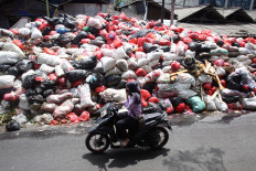A motorist passes by piles of garbage on Jl. Raya Otista in Cimanggis, South Tangerang, Banten, on Jan. 6, 2026. The South Tangerang city administration has struggled to manage the accumulating waste, which has persisted for the past month.