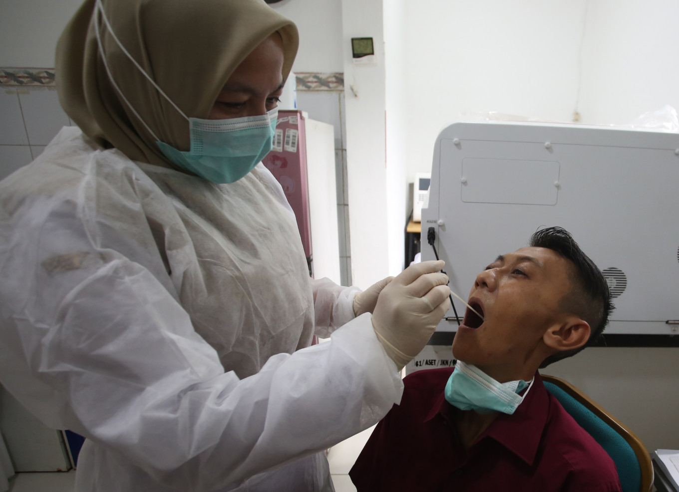 A healthcare worker performs a swab test on a patient during influenza symptom screening at a community health center (Puskesmas) in Serpong, South Tangerang, Banten, on Wednesday, Jan. 7, 2026. 