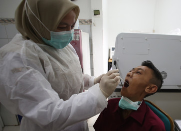 A healthcare worker performs a swab test on a patient during influenza symptom screening at a community health center (Puskesmas) in Serpong, South Tangerang, Banten, on Wednesday, Jan. 7, 2026. 