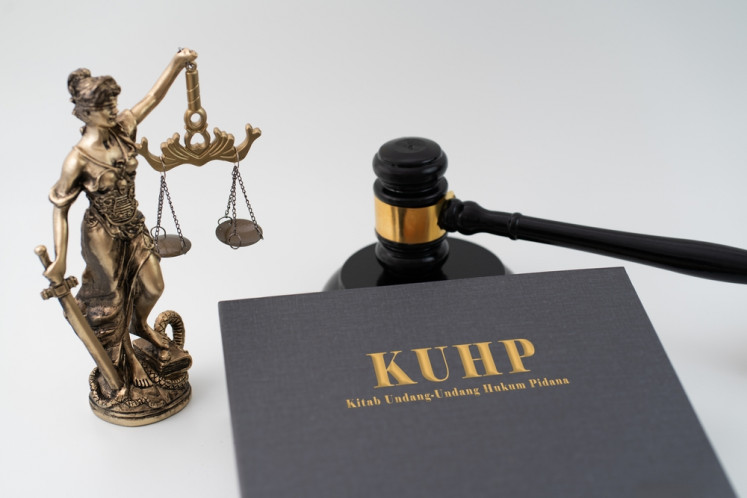 Illustration of a Criminal Code (KUHP) book next to a gavel and a Lady Justice statue.