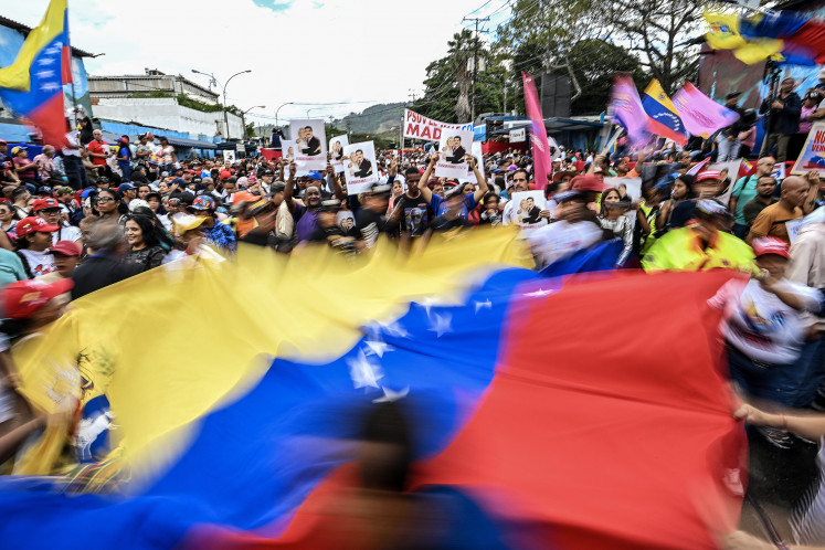 Demonstrators wave a giant national flag on Jan. 10, 2026, during a rally in Caracas to support Venezuelan President Nicolas Maduro, who was seized along with First Lady Cilia Flores in a United States military operation on Jan. 3 and flown to New York.