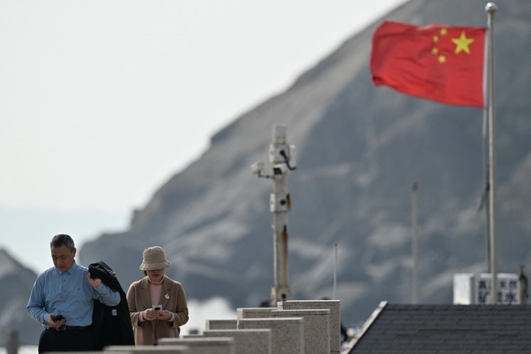 Visitors walk past a surveillance camera post (center) and a Chinese flag (right) on Pingtan Island, the closest point to Taiwan, on Dec. 30, 2025, in eastern China's Fujian province.