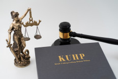 Illustration of a Criminal Code (KUHP) book next to a gavel and a Lady Justice statue.