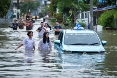 Residents inspect a taxi stranded by floodwaters on Jan. 12 in the Duta Bandara Permai housing complex, Kosambi, Tangerang Regency, Banten. According to the Tangerang Regency Regional Disaster Management Agency (BPBD), floods affected six sub-districts with water levels ranging from 30 to 140 centimeters, impacting approximately 1,014 households.