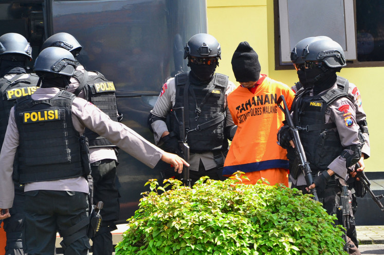 Indonesian policemen escort one of two terror suspects link to Central Jakarta's Sarinah bomb on March 2, 2016, in Malang, East Java. The 2016 bomb-and-gun assault on Central Jakarta's Sarinah area killed eight people, including four attackers. 