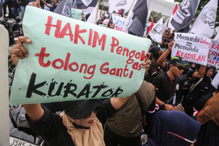 Former workers of textile company Sritex hold a banner on Jan. 12, 2026, during a protest in front of the Semarang District Court in Central Java.