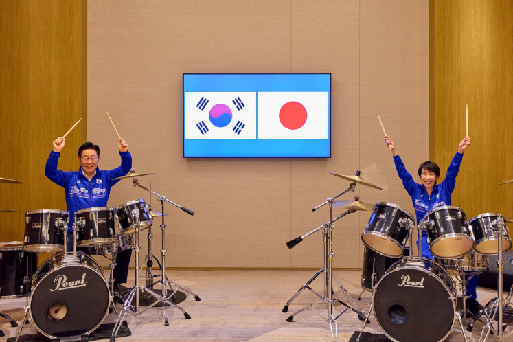 Japanese Prime Minister Sanae Takaichi (right) and South Korean President Lee Jae Myung pose on Jan. 12, 2026, for photographs before performing on drums after their meeting in Nara, Japan. 