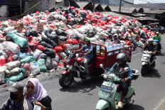 Motorists pass a pile of household waste on Jan. 6 in South Tangerang, Banten. The municipality administration has declared a waste emergency due to unmanaged waste generated across the city in the past month.