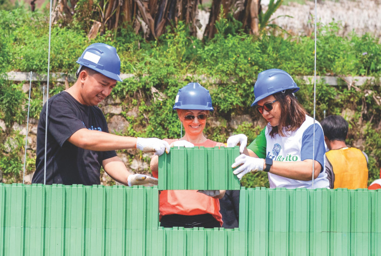Edo Irfandi (left), director of online donation platform Kitabisa.org, works with Sylvia Beiwinkler (center), CEO of Happy Hearts Indonesia, and Dian A. Purbasari, director of Bakti Barito Foundation, to install a plastic brick during a school rebuilding program for SDN 3 Barusari elementary school in Garut, West Java.