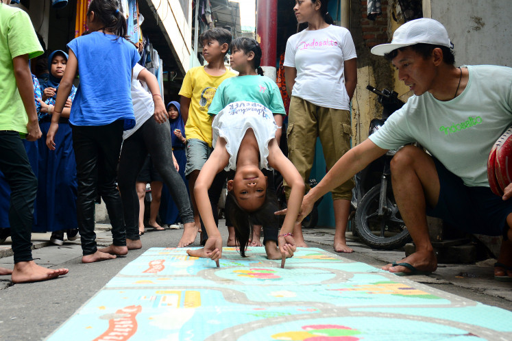 Fingertip balance: Adel, 11, an Indosalto participant, practices a backbend supported by her index fingers during an acrobatics training session on Jan. 15, 2026, in a narrow alley on Jl. Pluit Dalam III, Penjaringan, North Jakarta.