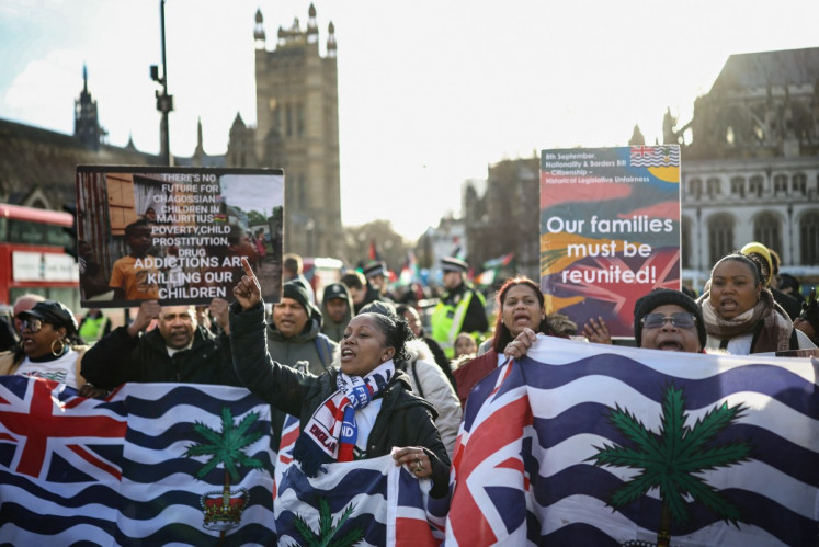 Supporters and members of the British Indian Ocean territory Chagos Archipelago hold placards and the territory's flag outside the Houses of Parliament in London on January 7, 2026, to protest against a proposed plan by the British government to hand over the islands to Mauritius. 