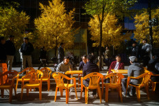 Customers sit at tables along a street as they wait for their orders from nearby cafes in Seoul on Nov. 14, 2025.