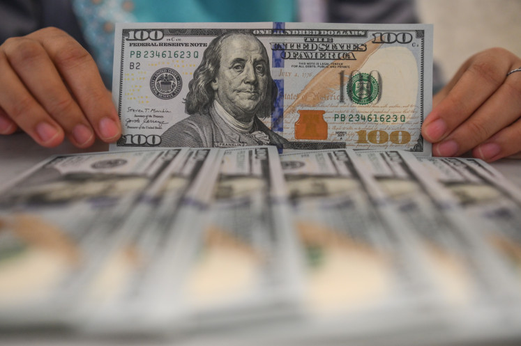 An employee displays U.S. dollar banknotes at Bank Syariah Indonesia in South Tangerang, Banten, Wednesday, Jan. 21, 2026. The rupiah strengthened 20 points, or 0.12 percent, to 16,936 per U.S. dollar at the close of trading on Wednesday, from 16,956 per dollar the previous day.