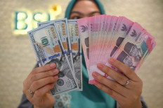 An employee displays Indonesian rupiah and United States dollar banknotes at Bank Syariah Indonesia in South Tangerang, Banten, on Jan. 21, 2026. 