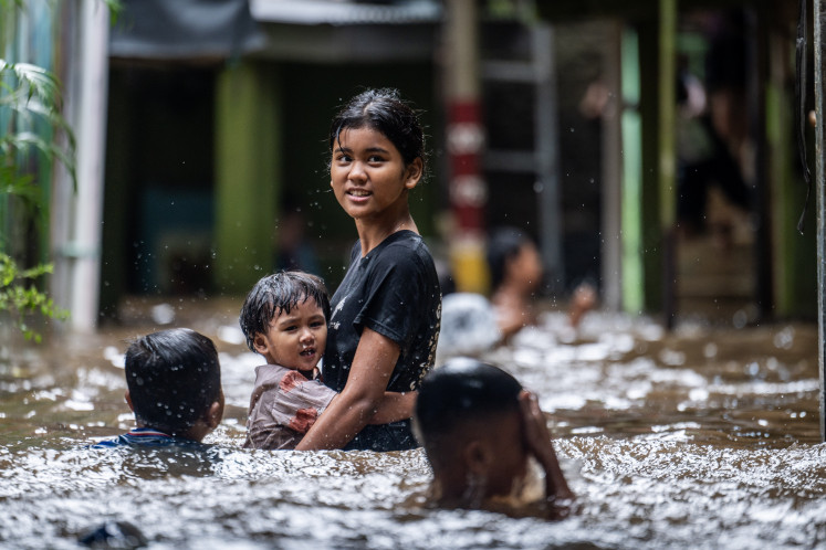 Children wade through floodwaters on Jan. 23, 2026 in the Kebon Pala neighborhood, Jatinegara, East Jakarta. Flooding from the Ciliwung River and Katulampa Dam in Bogor had submerged the area, with water reaching up to 130 centimeters.
