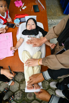 In good hands: Volunteers weigh a child before she receives a polio inoculation during a child stunting prevention program at an integrated services post in Banda Aceh, Aceh, on Nov. 14, 2022.
