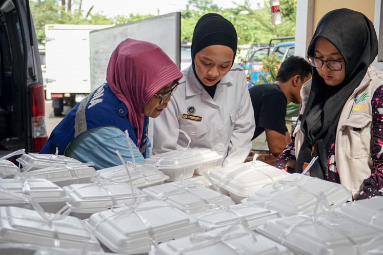 Workers from a Nutrition Service Unit (SPPG) distribute boxed meals to residents affected by flooding at the Pekalongan Social Affairs Agency in Central Java, on Jan 20, 2026.