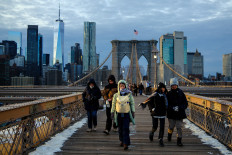 People brace the cold temperatures while walking on the Brooklyn Bridge in the Manhattan borough of New York City on January 21, 2026. Bringing icy temperatures, Winter Storm Fern will slam a massive stretch of the United States this week, with more than 175 million people facing the prospect of heavy snowfall, power outages and travel disruption. Forecasters warned it could be 3,219 kilometers long, well over half the length of the continental US.
