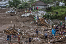 Residents clear debris on Jan. 24, 2026, while searching for victims of a landslide in Pasirlangu village, Cisarua, West Bandung regency, West Java.