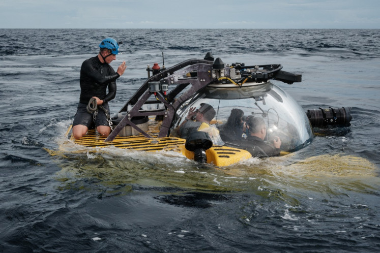 This photo taken on January 12, 2026 shows the crew of the OceanXplorer, a research vessel operated by the marine non-profit OceanX, coordinating safety protocols with a submersible pilot before a deep-sea operations in the waters off Sulawesi island. 