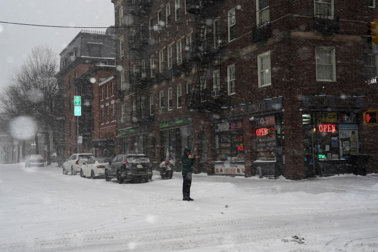 A pedestrian uses his mobile phone to photograph snowfall, as Winter Storm Fern stretches across a large swath of the United States, in Brooklyn, New York City, US, January 25, 2026. 