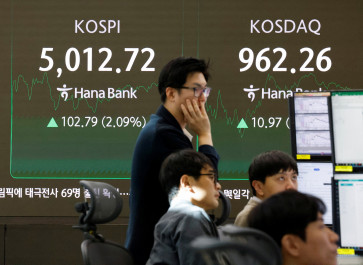 Currency dealers work in front of an electronic board displaying the Korea Composite Stock Price Index (KOSPI) over 5,000 points in the dealing room of a bank, in Seoul on Jan. 22, 2026. 