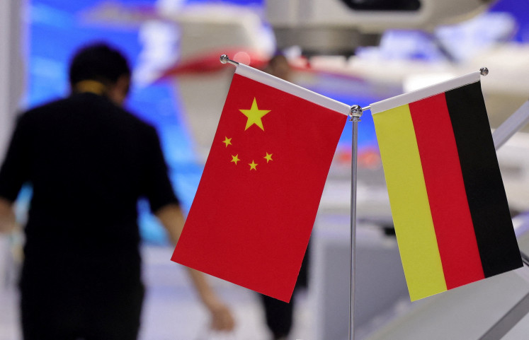 A person walks next to the national flags of China and Germany at the 8th China International Import Expo (CIIE) in Shanghai, China, on Nov. 5, 2025.