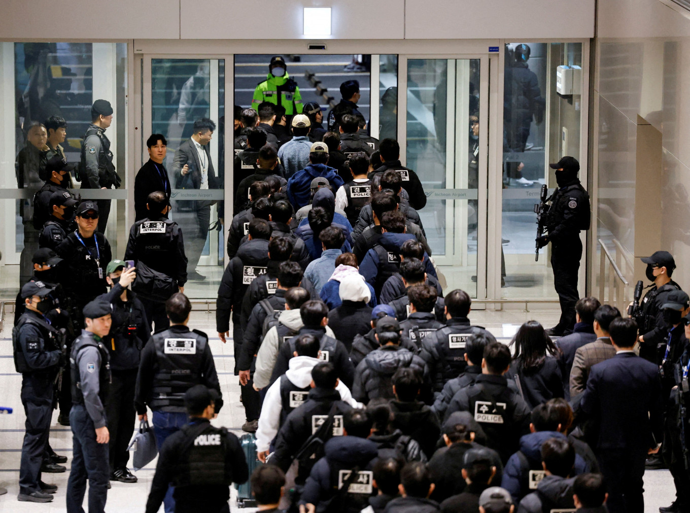 Police officers escort South Koreans allegedly involved in scam operations in Cambodia after being forcibly repatriated from Cambodia, at Incheon International Airport in Incheon, South Korea January 23, 2026.