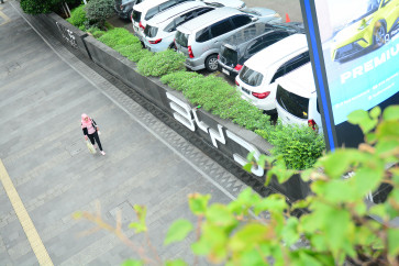 A woman walks past a BYD sign on Jan. 27 outside an electric vehicle dealership on Jl. Sudirman in Central Jakarta.