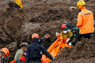Rescue members carry a body bag containing the remains of a victim from the site of a landslide following heavy rains in Pasirlangu village, West Bandung regency, West Java, on January 27, 2026.