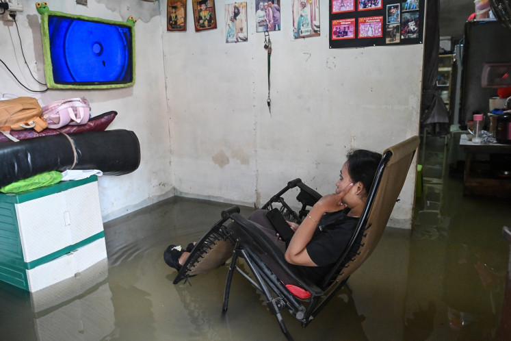 A woman watches television on Jan. 29, 2026, in her flooded house in Cengkareng, West Jakarta, which was among the worst-hit municipalities affected by flooding due to heavy overnight rain across Greater Jakarta.