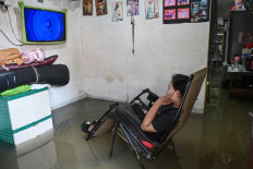 A woman watches television on Jan. 29, 2026, in her flooded house in Cengkareng, West Jakarta, which was among the worst-hit municipalities affected by flooding due to heavy overnight rain across Greater Jakarta.