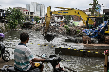 A worker operates an excavator for dredging at the Grogol River in Kemanggisan, West Jakarta, on Jan. 28, 2026.