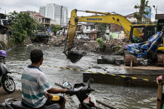 A worker operates an excavator for dredging at the Grogol River in Kemanggisan, West Jakarta, on Jan. 28, 2026.