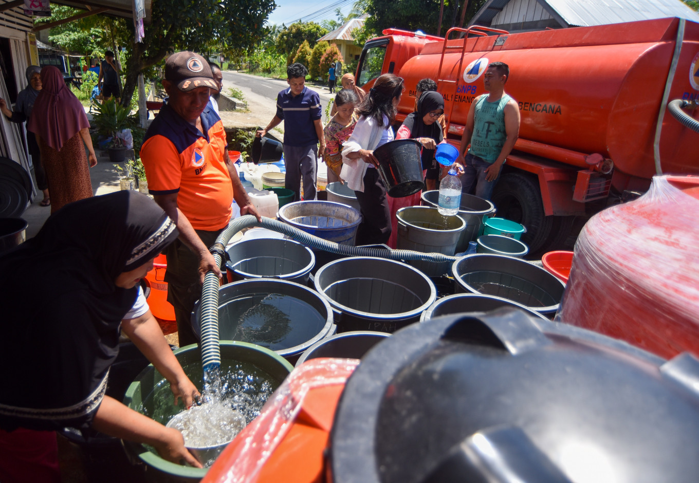 A Padang Disaster Mitigation Agency worker fills buckets with clean water on Jan. 18 for residents in Vila Tarok, Pasa Ambacang, Kuranji district, Padang, West Sumatra. The Pauh and Kuranji districts are facing a clean water crisis after wells dried up and dams and irrigation systems were damaged by flooding in Nov. 2025.