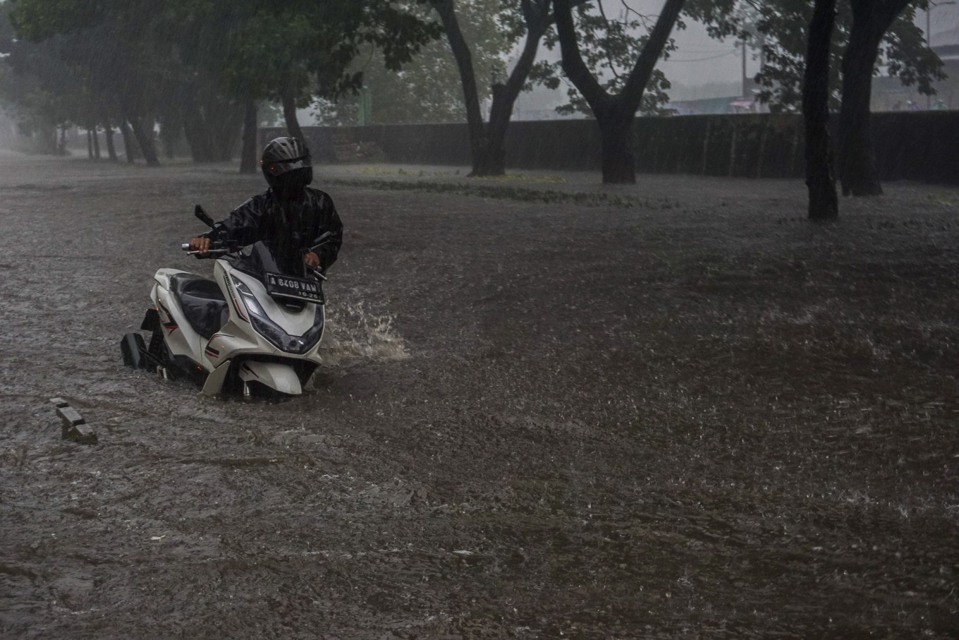 A motorist pushes his motorcycle through floodwater on the inundated Jl. Daan Mogot in West Jakarta on Jan. 22, 2026. Heavy rain and bad drainage triggered floods of up to 60 centimeters in depth in the area.