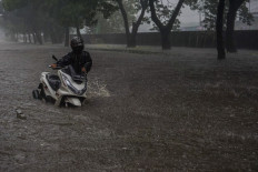 A motorist pushes his motorcycle through floodwater on the inundated Jl. Daan Mogot in West Jakarta on Jan. 22, 2026. Heavy rain and bad drainage triggered floods of up to 60 centimeters in depth in the area.