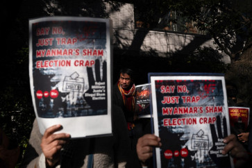 A demonstrator looks on as others holds placards that read &ldquo;Say no, just trap - Myanmar's sham election crap&ldquo; during a rally outside the Myanmar embassy in Tokyo, Japan on Dec. 28, 2025 protesting against Myanmar's general election staged by the country's military government. Myanmar's heavily restricted polls began on Dec. 28, with the ruling junta touting the exercise as a return to democracy five years after it ousted the last elected government, triggering renewed nationwide conflict.