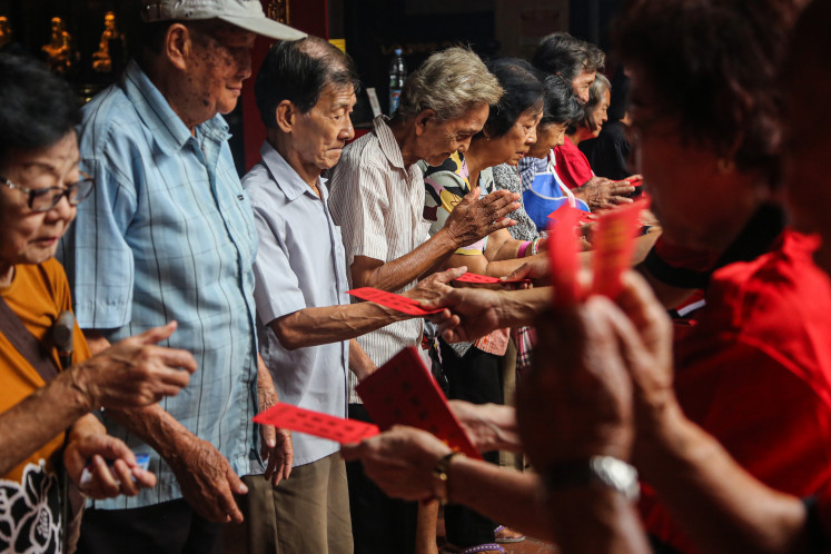 Everyone wins: Elderly residents receive cash-filled red envelopes from Tay Kak Sie Chinese Temple Foundation officials on Feb. 1 during an event to distribute angpao at the grand temple in Semarang, Central Java. The tradition also includes the distribution of basic food staples for about 1,500 elderly people and underprivileged residents as an expression of social care ahead of the Lunar New Year.