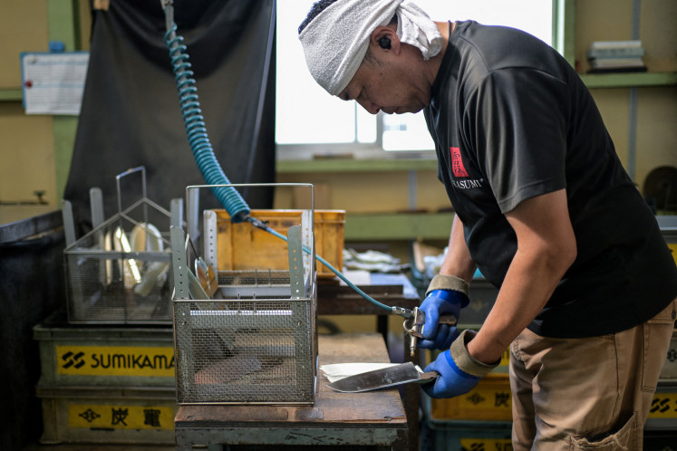 An employee for Japanese knife manufacturer Sumikama Cutlery washes and dries blades at their factory in Seki, Gifu prefecture, north of Nagoya, on July 22, 2025.
