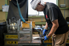An employee for Japanese knife manufacturer Sumikama Cutlery washes and dries blades at their factory in Seki, Gifu prefecture, north of Nagoya, on July 22, 2025.