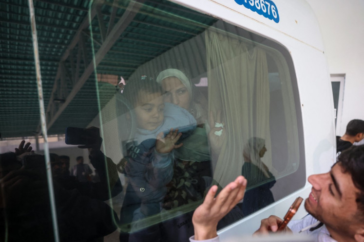 A Palestinians child waves from the window of a bus evacuating war-wounded and patients, accompanied by relatives, as they ready to leave the Gaza Strip for treatment abroad through the Rafah border crossing between Gaza and Egypt, the day after it was opened by Israel for a limited number of people, in Khan Yunis, in the southern Gaza Strip on February 2, 2026. Gaza's key Rafah border crossing reopened to Palestinians on February 2, an Israeli security official said, though Egyptian state-linked media said only 50 people would be allowed to cross in each direction in the early days. 