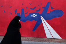 A woman walks on Feb. 1, 2026, past a mural depicting a United States drone painted on the outer walls of the former US Embassy in Tehran, colloquially referred to as the &ldquo;Spy Den&rdquo;.