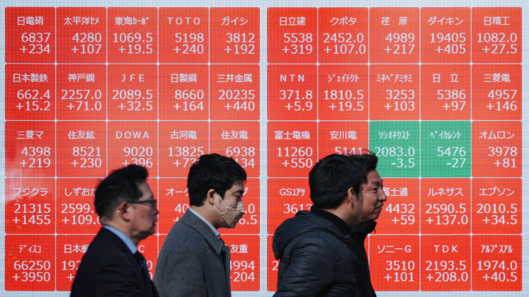 Pedestrians walk past an electronic quotation board displaying the Nikkei 225 stock prices on the Tokyo Stock Exchange in Tokyo on Feb. 3, 2026.