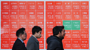 Pedestrians walk past an electronic quotation board displaying the Nikkei 225 stock prices on the Tokyo Stock Exchange in Tokyo on Feb. 3, 2026.