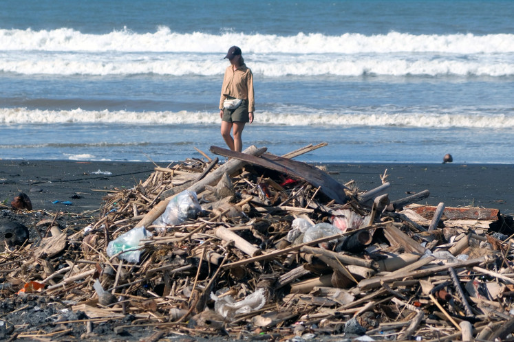A tourist walks near piles of trash on Feb. 3, 2026, at Yeh Gangga Beach in Tabanan, Bali. President Prabowo Subianto has highlighted environmental problems in Bali, citing pollution from waste and urging local administrations to involve students in cleanup activities as part of efforts to address the issue and preserve the island&rsquo;s tourist sector.