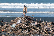 A tourist walks near piles of trash on Feb. 3, 2026, at Yeh Gangga Beach in Tabanan, Bali. President Prabowo Subianto has highlighted environmental problems in Bali, citing pollution from waste and urging local administrations to involve students in cleanup activities as part of efforts to address the issue and preserve the island&rsquo;s tourist sector.