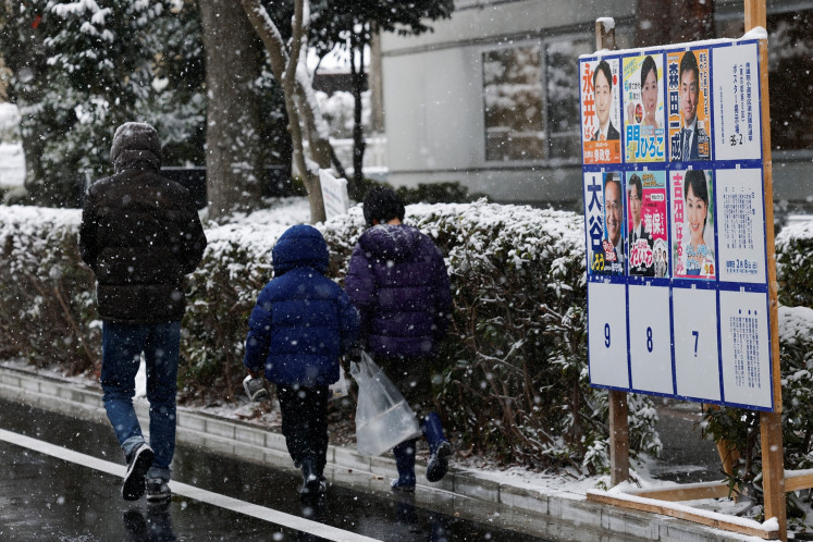 A family walks past election posters displayed near a polling station on the day of a general election in Tokyo, Japan, on Feb. 8, 2026.