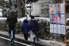 A family walks past election posters displayed near a polling station on the day of a general election in Tokyo, Japan, on Feb. 8, 2026.