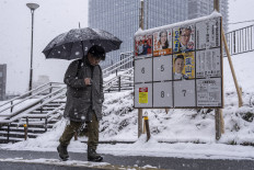 A man walks past a board displaying posters of candidates for the House of Representatives election during snowfall in Tokyo on Feb. 8, 2026.